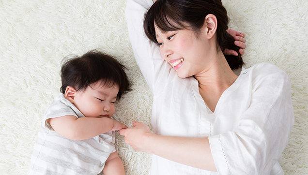 A mother laying on the floor with a newborn baby