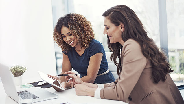Two woman looking at a tablet computer and smiling