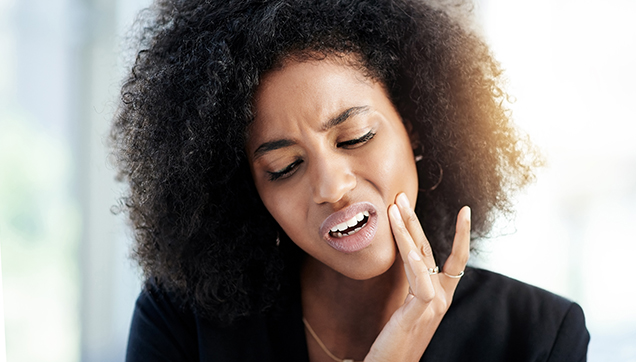 A woman touching her jaw and wincing in pain