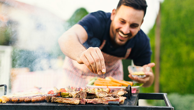 A man seasoning food on a grill