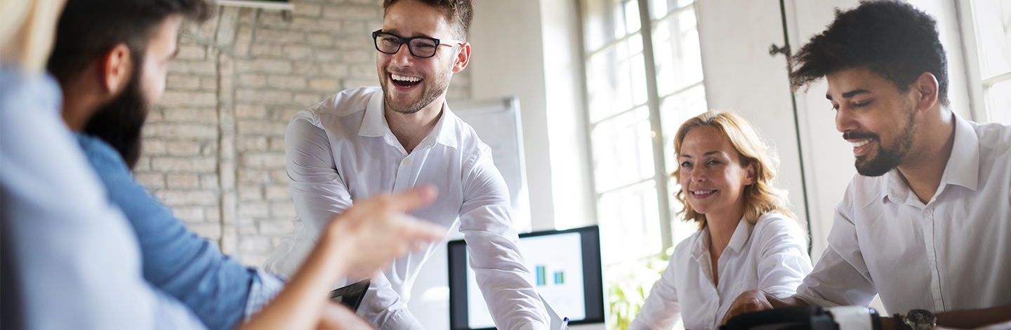 A group of employees sitting around a conference table laughing