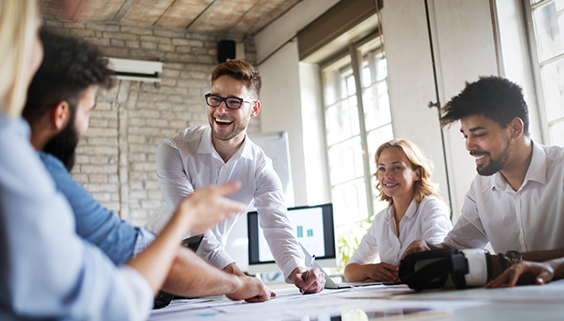 A group of employees sitting around a conference table laughing