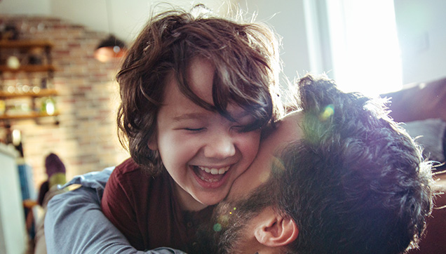 A father and son laughing in their living room