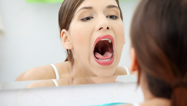 A woman looking at her mouth in a mirror