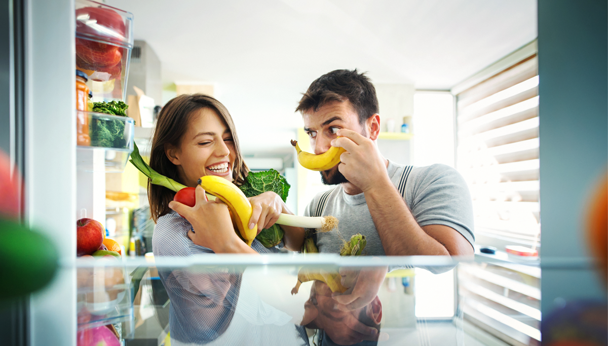 A couple with their hands full of vegetables and fruits