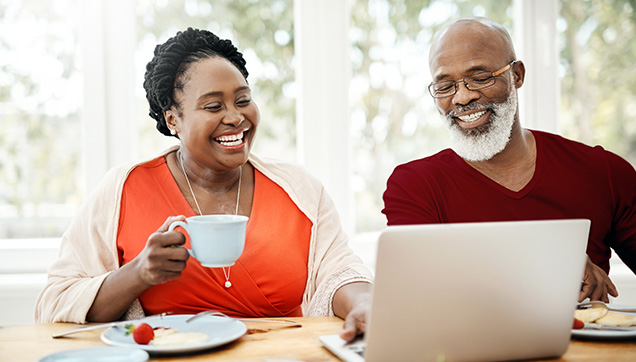 A couple looking at a laptop and smiling