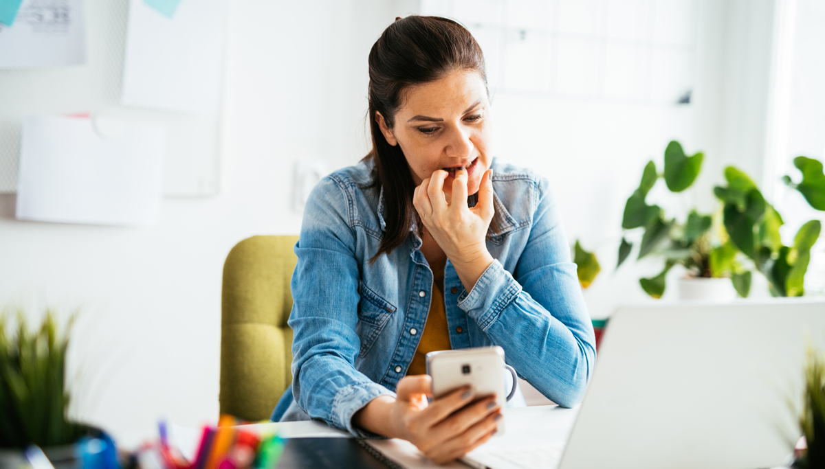 A woman sitting at a desk and biting her fingernails