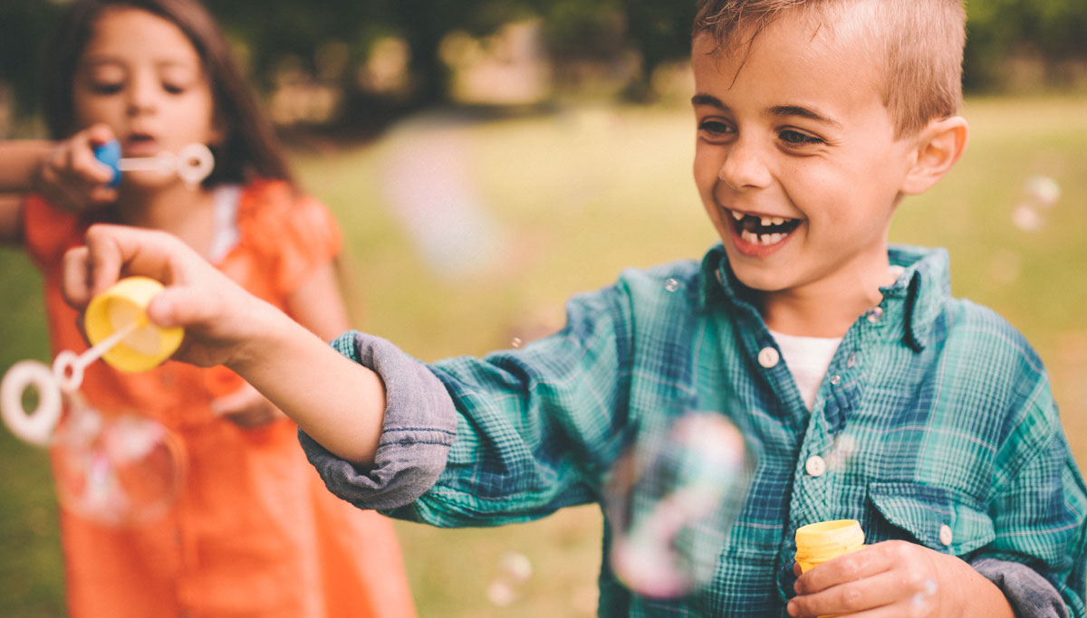 Two children blowing bubbles outside