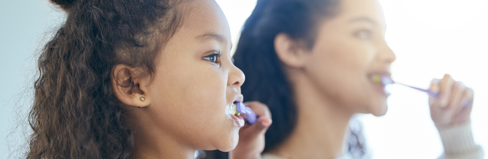A mother and daughter brushing their teeth