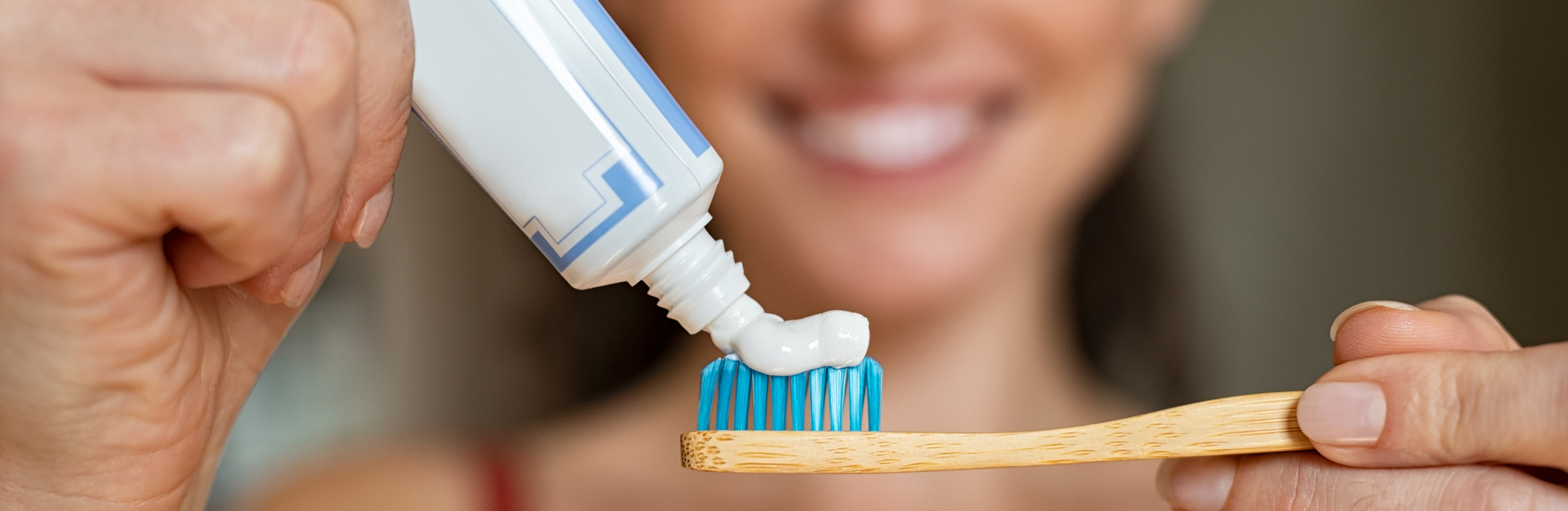 A woman applying toothpaste to a toothbrush