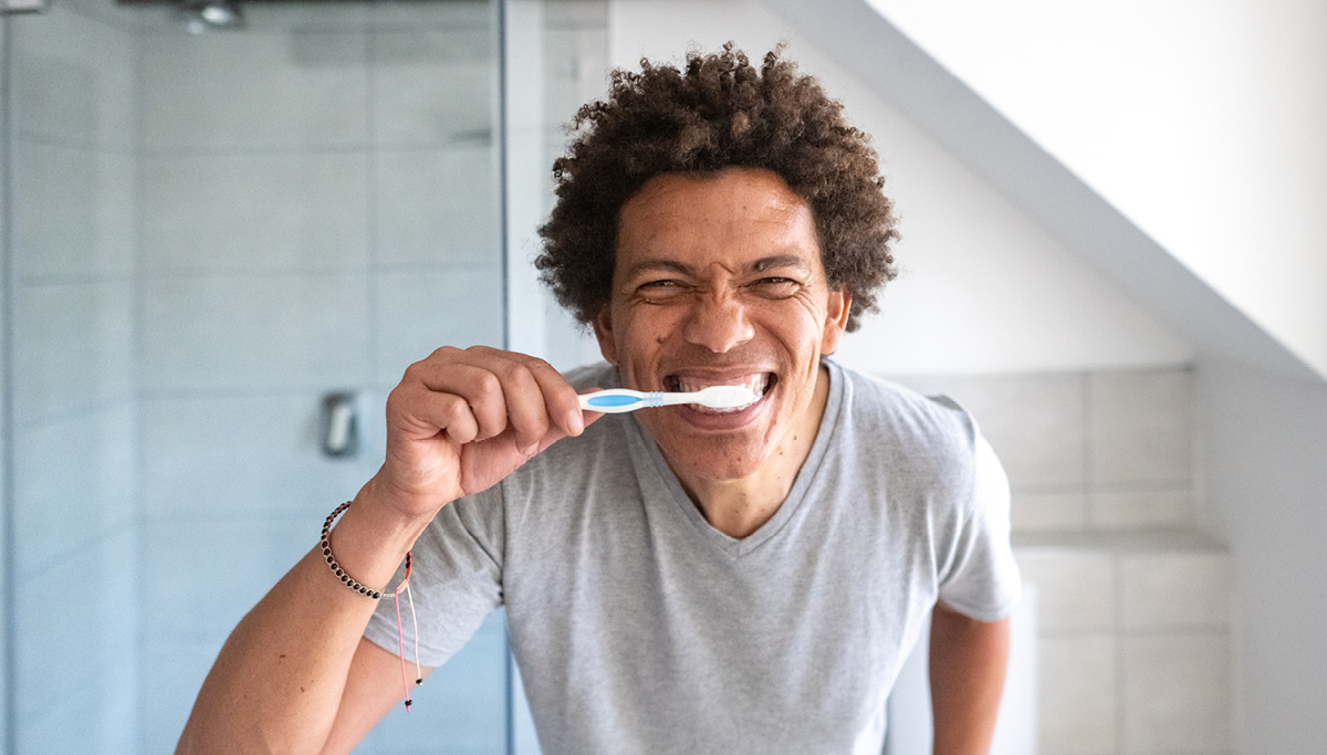 A man brushing his teeth in a mirror