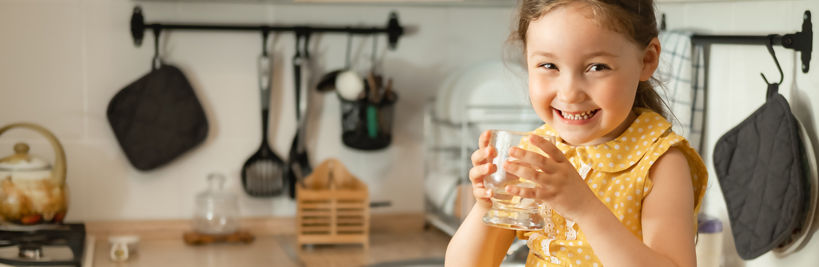 A girl drinking a glass of water in a kitchen