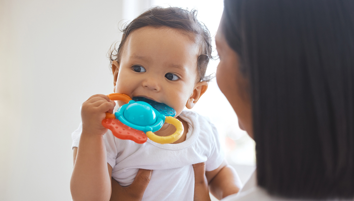 A baby teething on a toy