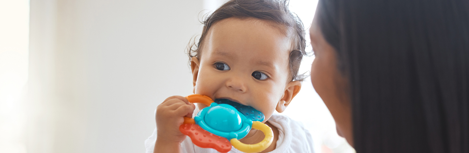 A baby teething on a toy