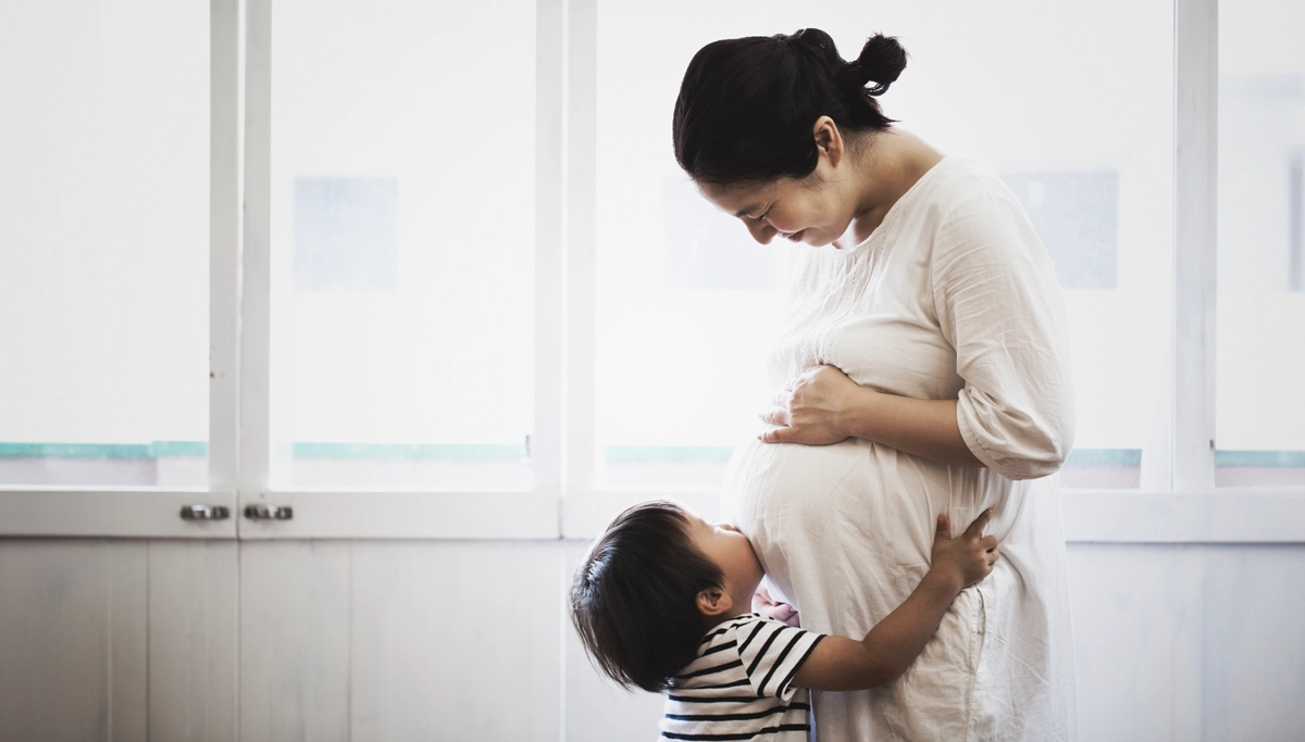 A child pushing their face into their mother's pregnant belly