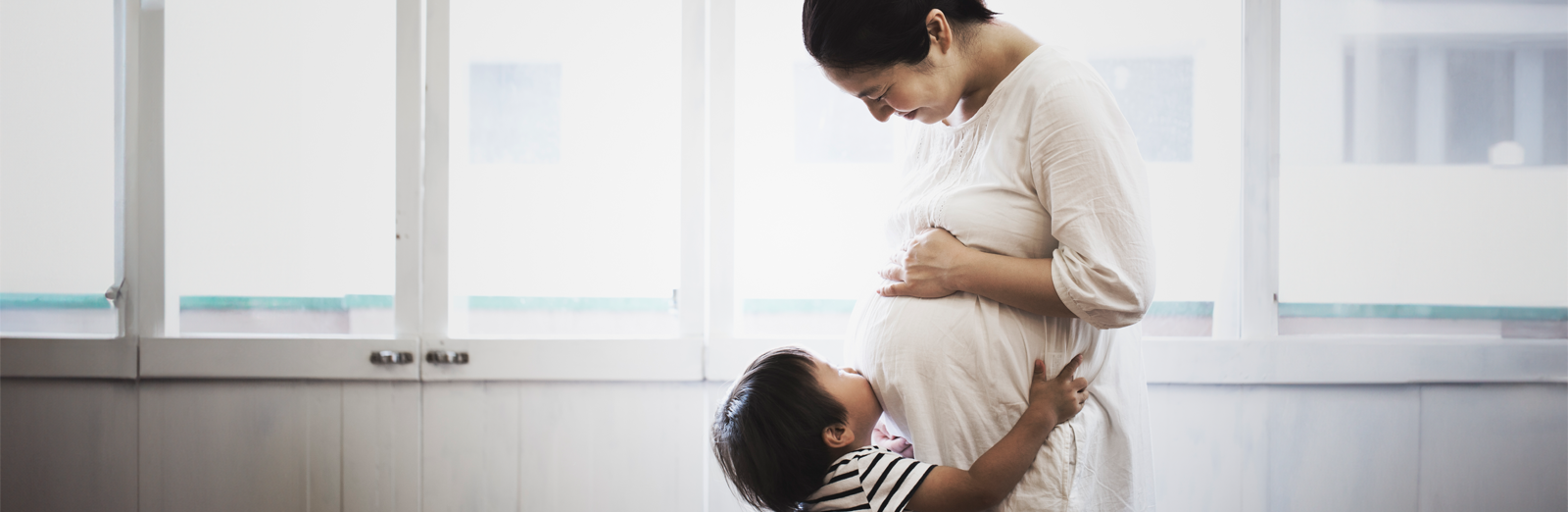 A child pushing their face into their mother's pregnant belly