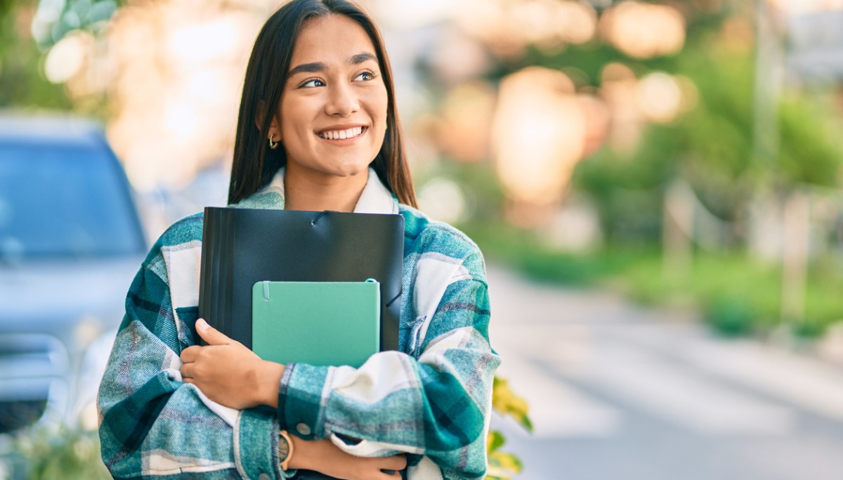 A girl carrying books and smiling