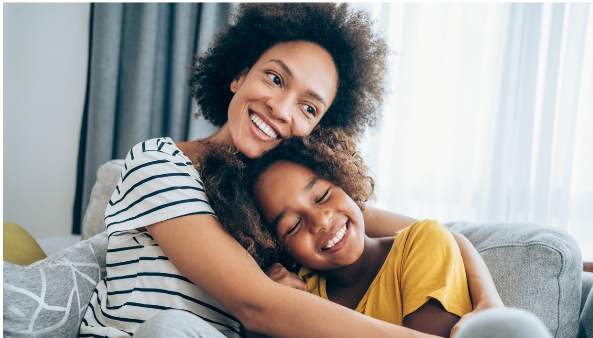 A mother and daughter sitting on a couch and hugging