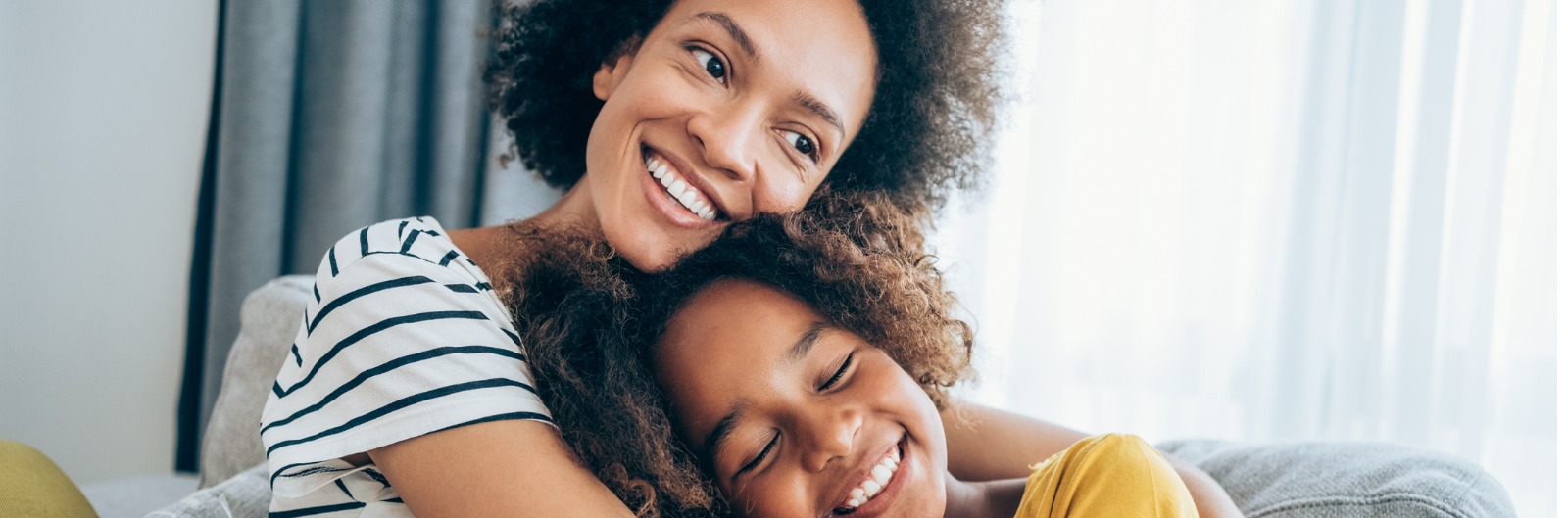 A mother and daughter sitting on a couch and hugging