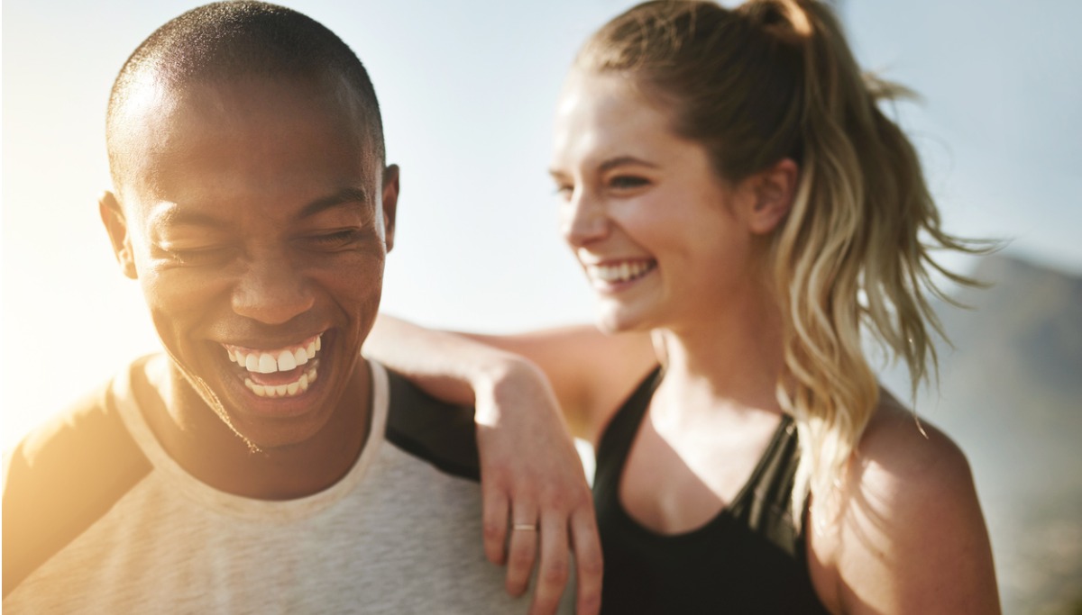 A man and woman laughing outside in the sun