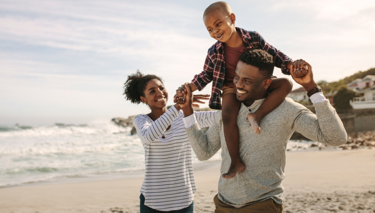 A family smiling together out in the sun.