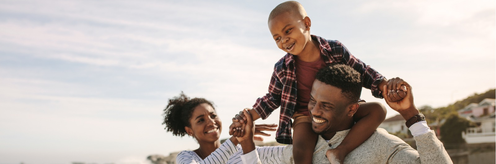 A family smiling together out in the sun.
