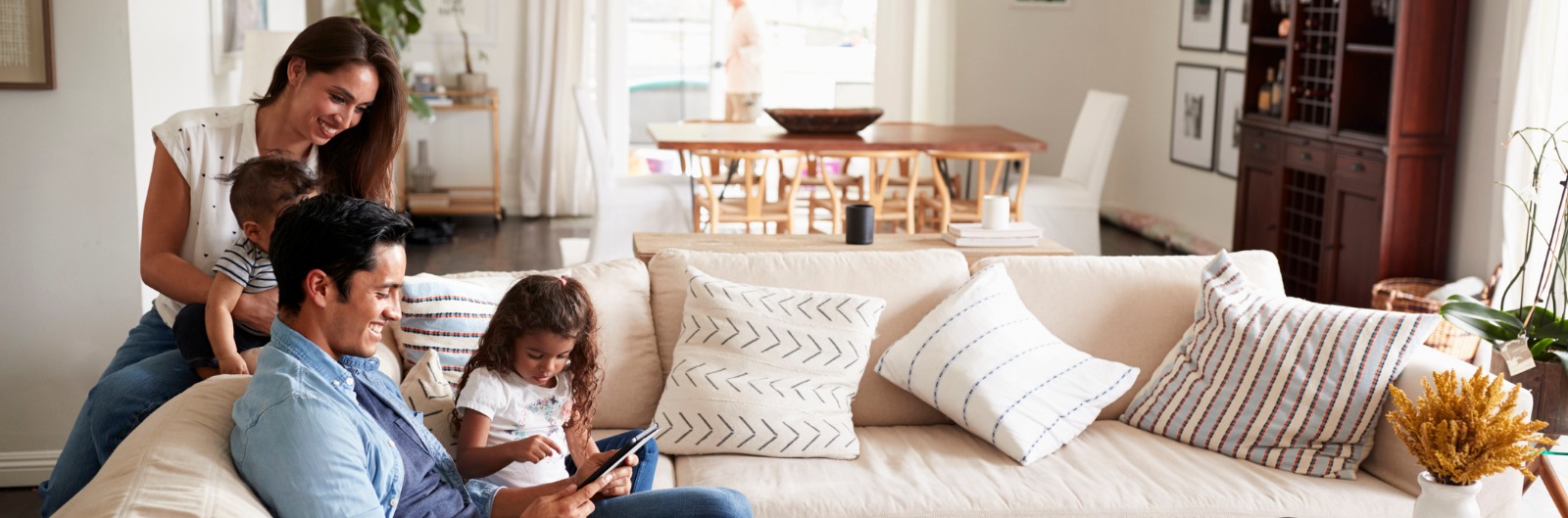 A family sitting together on a counch while looking at a tablet device