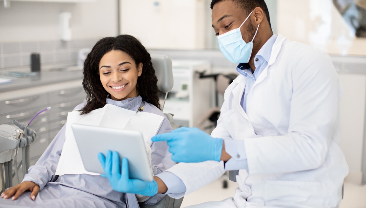 A dentist explaining information to a patient on a tablet device