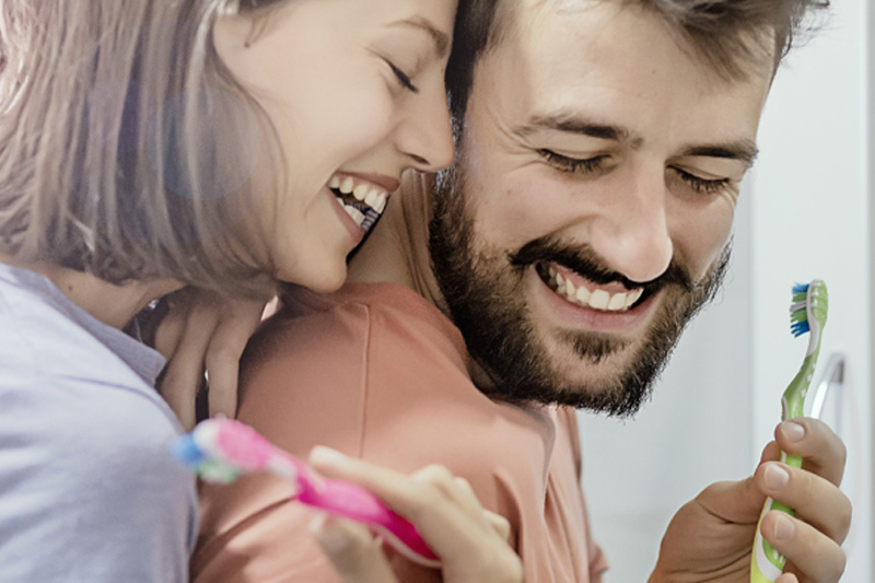 A couple brushing their teeth and laughing together