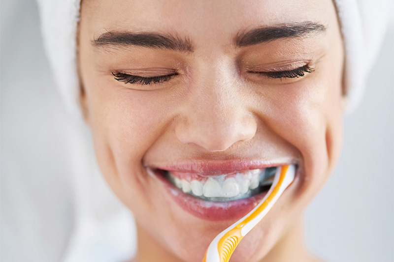 A woman smiling and brushing her teeth