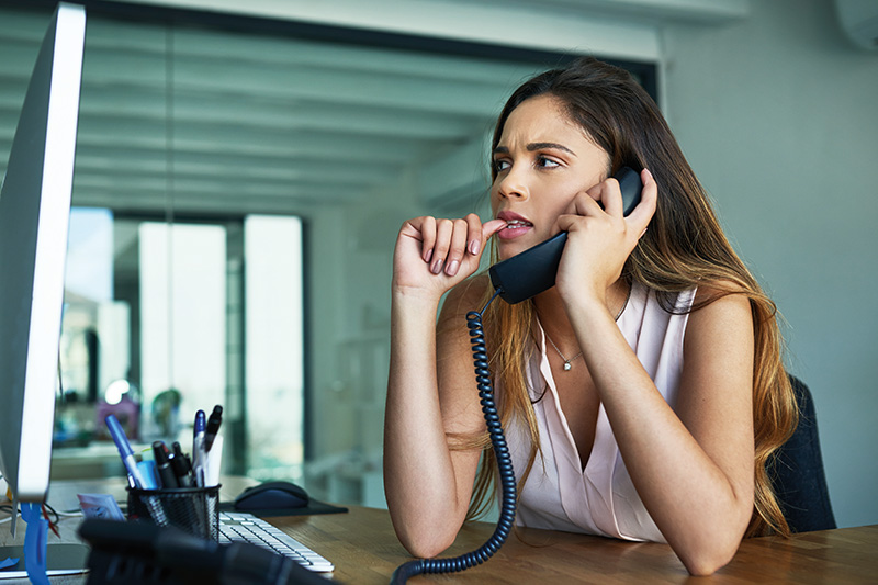 A woman biting her nails while on a phone call