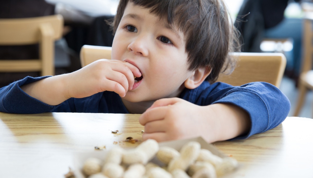 A child eating peanuts at a table