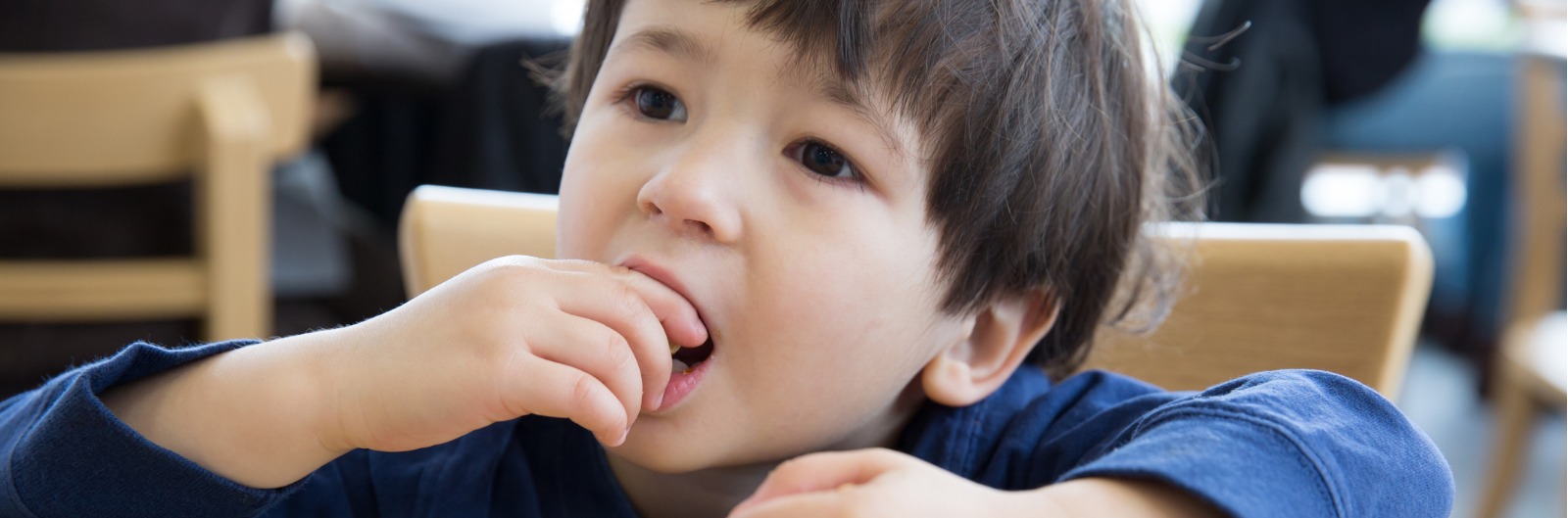 A child eating peanuts at a table