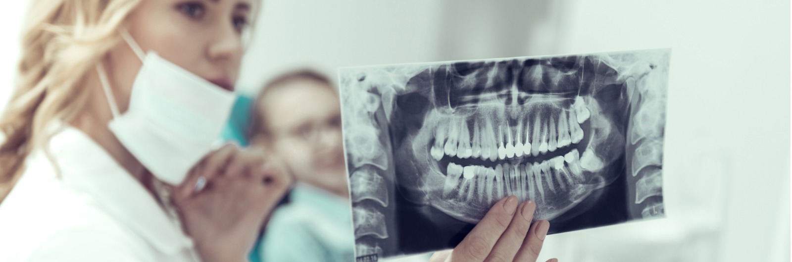 A dentist looking at an x-ray of a mouth
