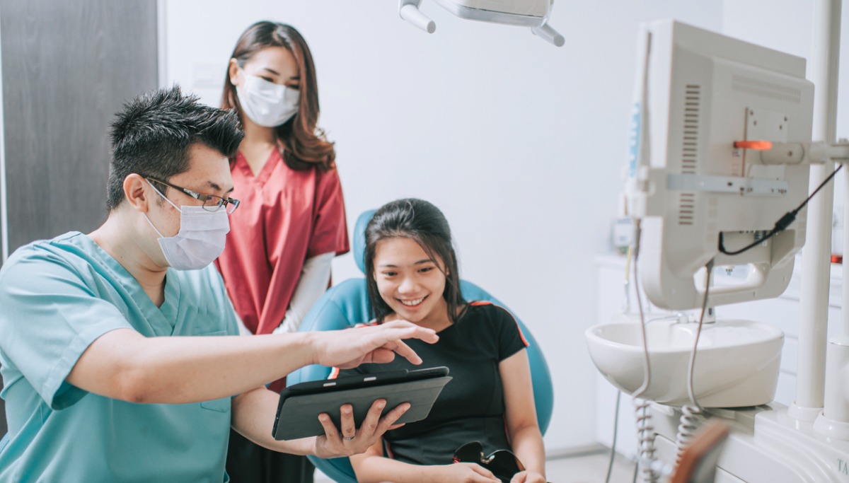 A dentist showing a young girl an xray on a tablet
