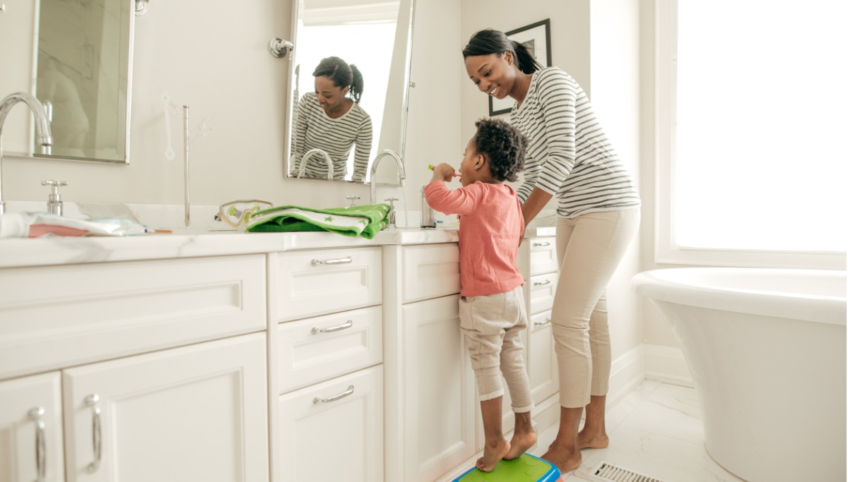 A mother watching her daughter brush her teeth
