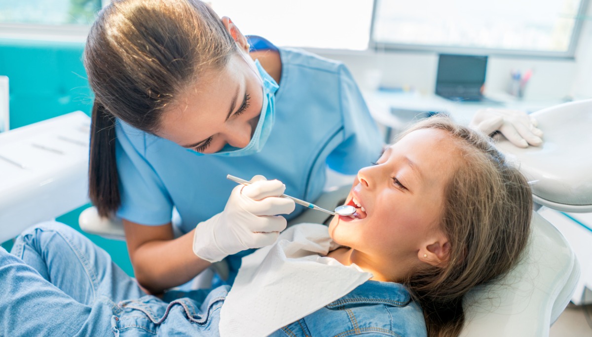 A dentist conducting an exam on a young patient