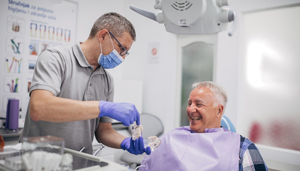 A patient and dentist laughing as they look at a denture