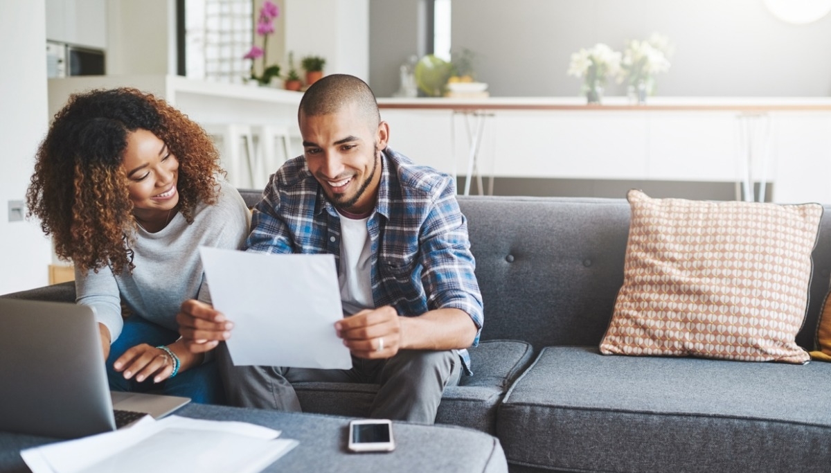 A couple sitting on a couch looking at their benefits