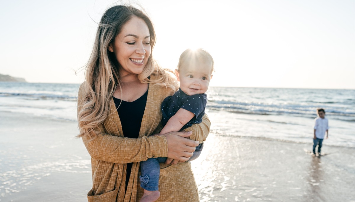 A mother carrying a baby at the beach