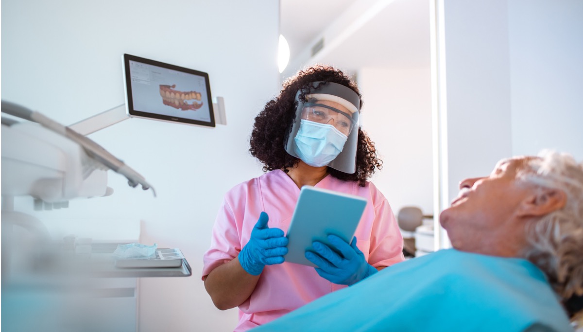 A dentist showing a patient a diagram of a mouth