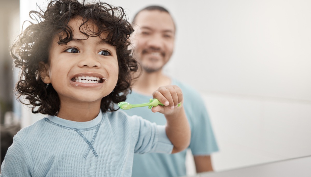 A father and child brushing their teeth in the mirror