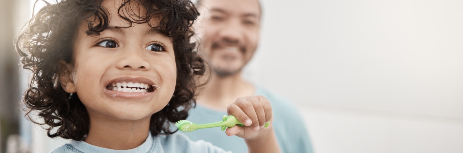 A father and child brushing their teeth in the mirror