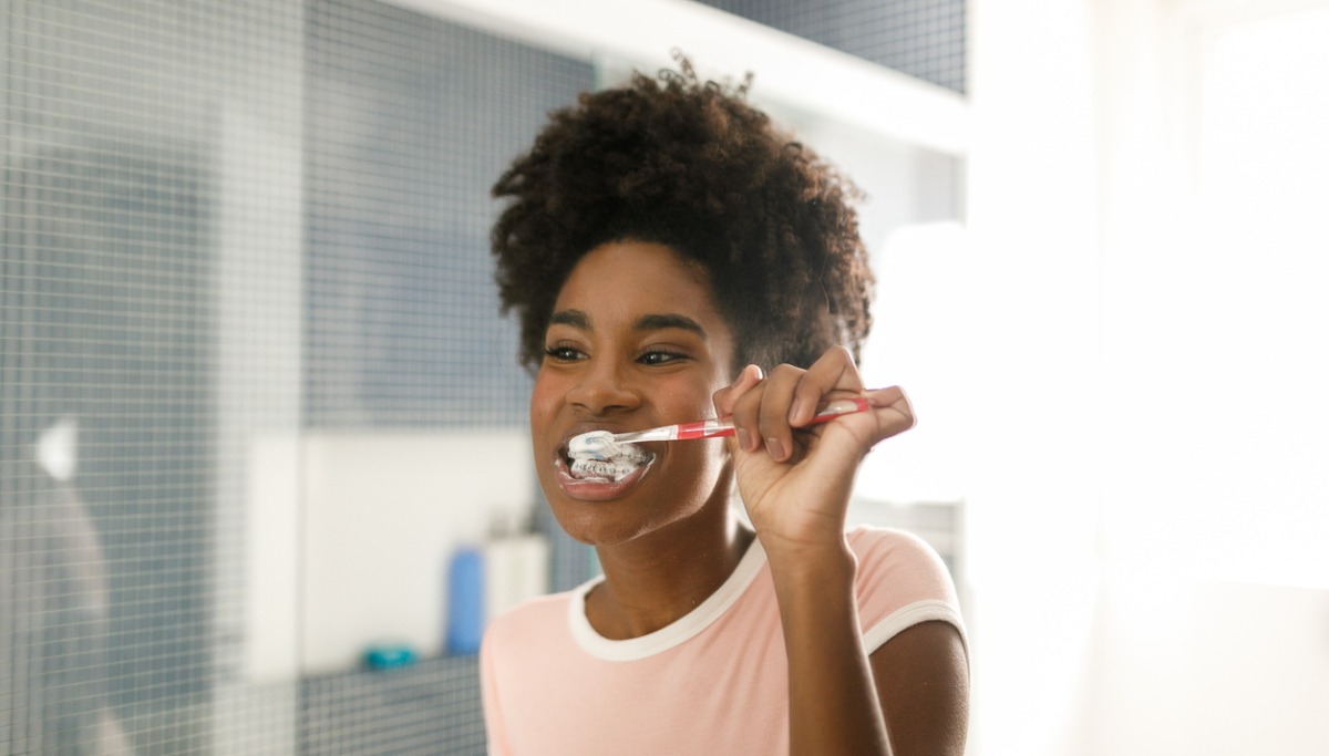 A girl with braces brushes her teeth
