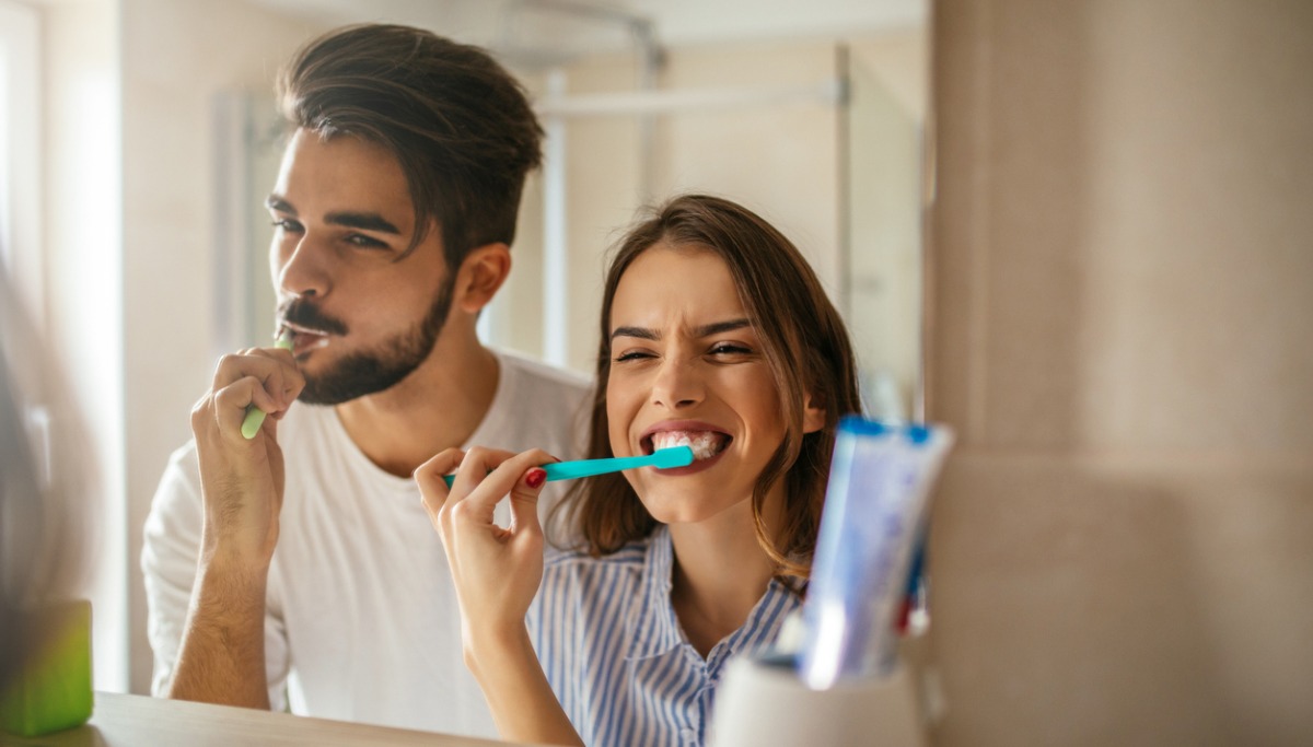A couple brushing their teeth in a mirror
