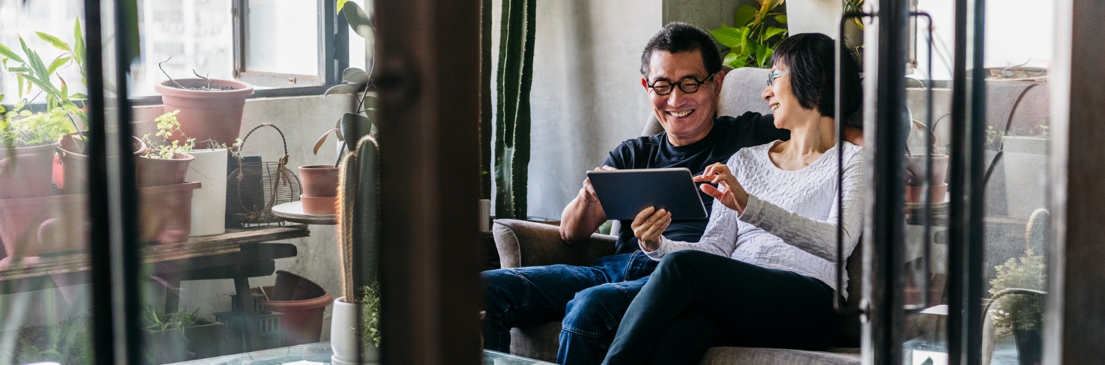 A couple sitting in a garden space looking at a tablet device.