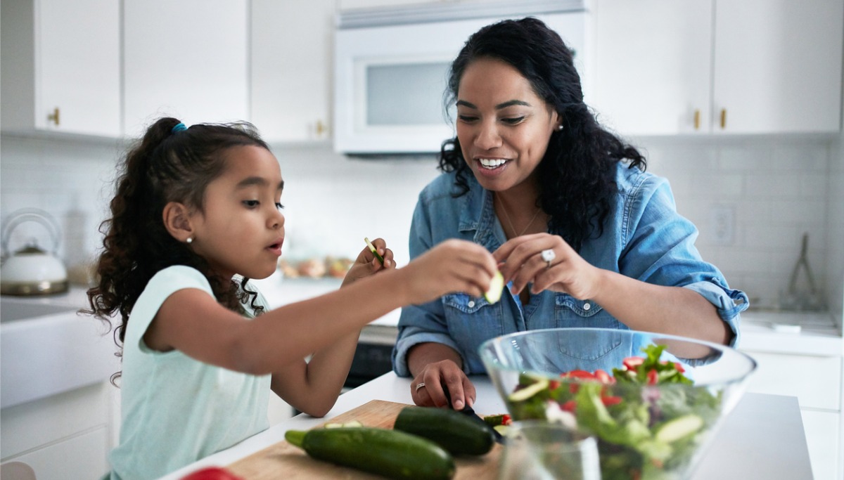 A mother and child making salad in a kitchen