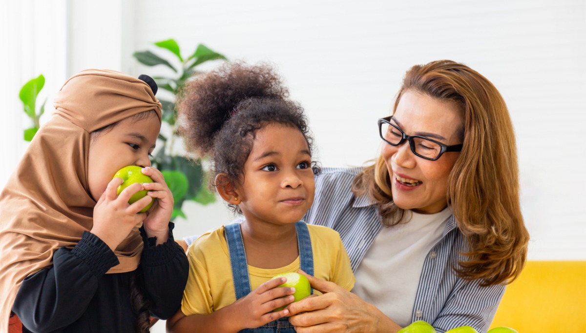 A woman and two kids eating apples