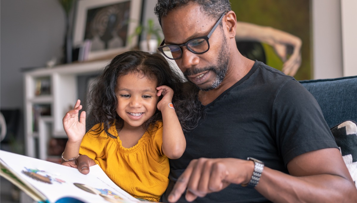 A father reading a book to his daughter