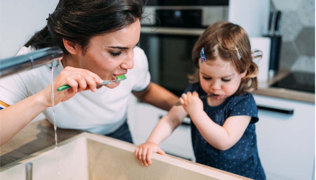 A mother and daughter brushing their teeth